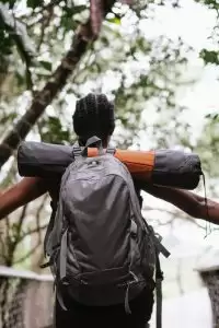 A woman with a backpack enjoys a scenic hike on a forested trail, embracing nature's wonders.