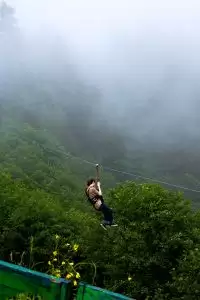 Woman ziplining through misty forest in Tanzania, offering a thrilling adventure experience.